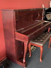 Load image into Gallery viewer, Upright piano with a brown bench against a red wall