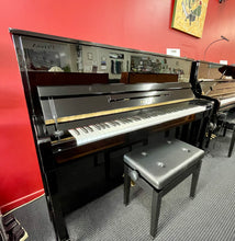 Load image into Gallery viewer, Black upright piano with a bench in a room with red walls and a painting.