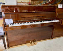 Load image into Gallery viewer, Yamaha upright piano in a showroom setting with a price tag visible.