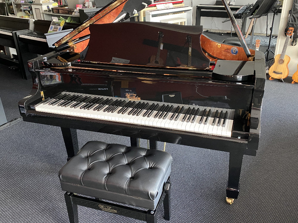 Black piano with a matching black bench in a showroom setting