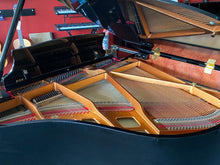Load image into Gallery viewer, Close-up of a grand piano with visible strings and wooden finish.
