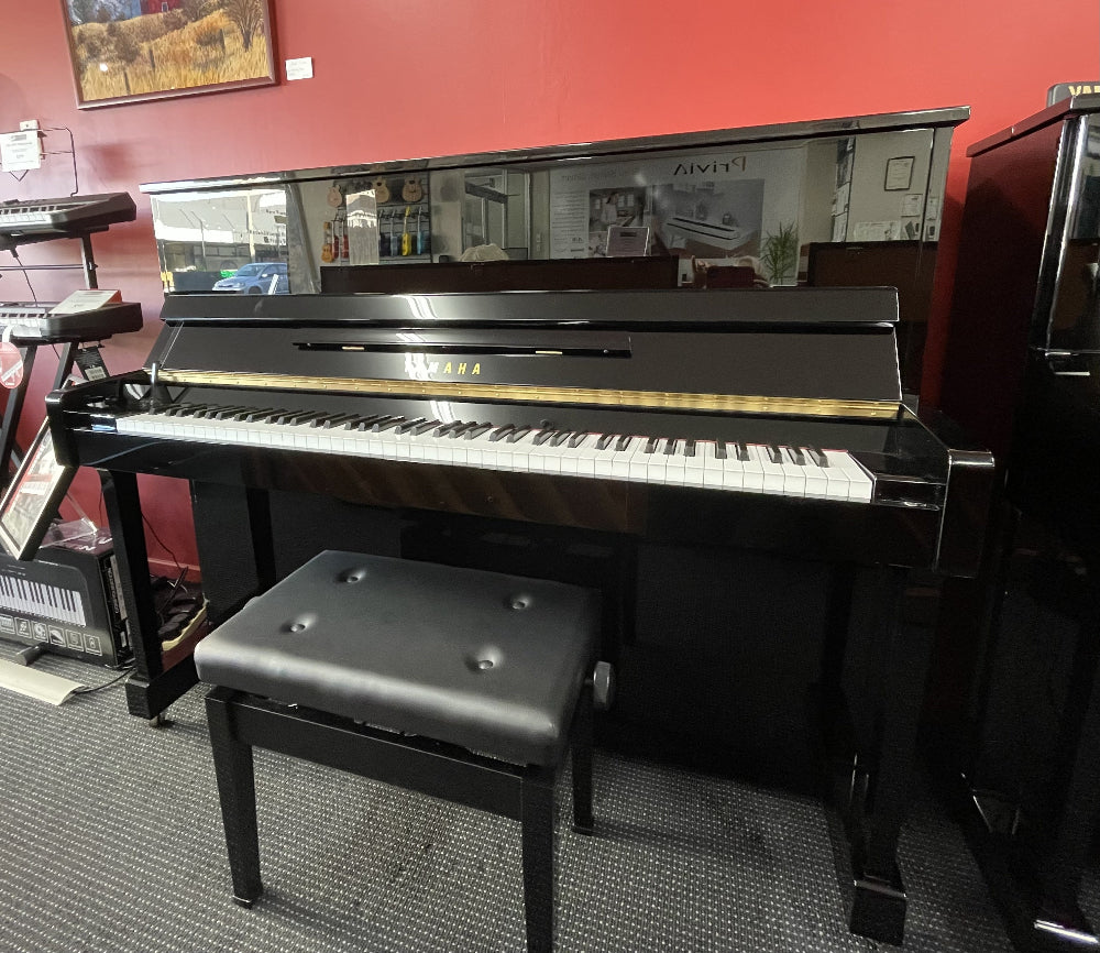 Black upright piano with a bench in a room setting